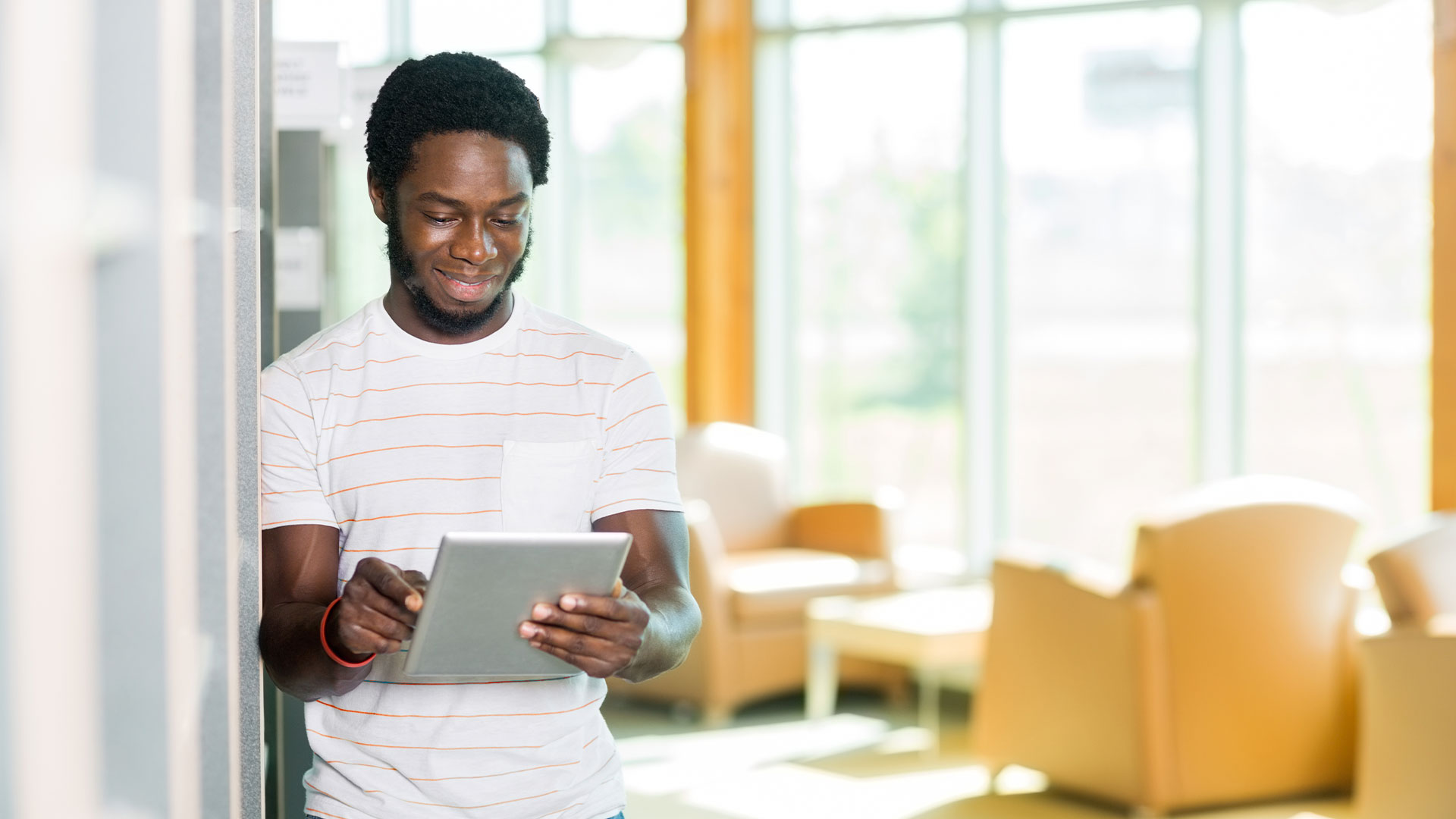 Male student reading newsletter on tablet