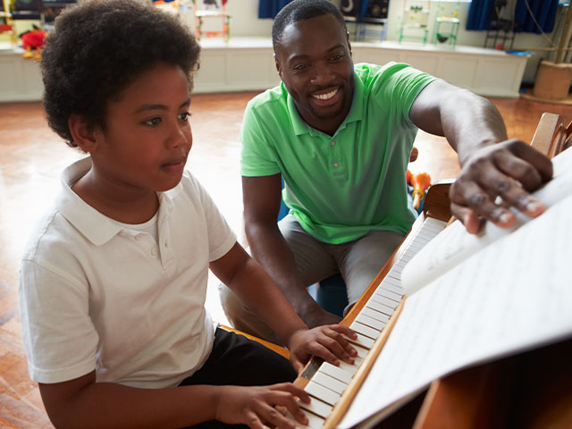 Teacher giving student piano lessons